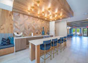 Thumbnail 13 of 35 - a bar with blue stools in a large room with a counter and chairs