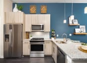 Thumbnail 5 of 41 - A modern kitchen with a stainless steel refrigerator and a microwave above the stove.