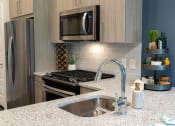 Thumbnail 9 of 41 - A kitchen with a granite countertop and stainless steel appliances.
