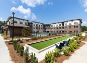 Thumbnail 40 of 41 - a courtyard with a lawn and chairs in front of an apartment building