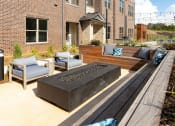 Thumbnail 39 of 41 - a patio with a firepit and furniture in front of a brick building