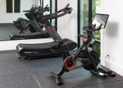 Thumbnail 24 of 41 - A black and red exercise bike is in a room with a grey floor.
