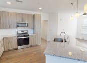 Thumbnail 6 of 41 - A kitchen with a granite countertop and stainless steel appliances.