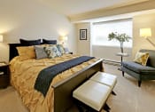 Thumbnail 9 of 28 - a bedroom with a bed and a chair and a window