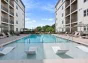 Thumbnail 6 of 27 - a swimming pool with chairs in front of a building