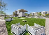 Thumbnail 49 of 59 - a park with lawn furniture and a building in the background at Element 12 Apartments, Henderson NV