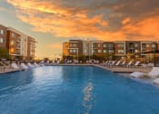 Thumbnail 10 of 59 - Evening pool lounge area with chairs and a sunset background at Element 12 Apartments, Henderson NV
