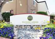 Thumbnail 37 of 55 - A sign for a garden apartment complex with a red door in the background at Hillsdale Garden Apartments, San Mateo