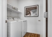 Thumbnail 15 of 42 - a small laundry room with a washer and dryer and a painting on the