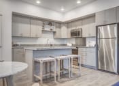 Thumbnail 1 of 42 - a kitchen with stainless steel appliances and a bar with three stools