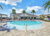 Thumbnail 2 of 30 - Resort-style pool surrounded by palm trees and lounge chairs at The Charles in Destin