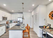 Thumbnail 19 of 30 - Contemporary apartment kitchen with white cabinetry, island and pendant lighting