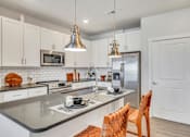 Thumbnail 20 of 30 - Contemporary apartment kitchen with white cabinetry, island and pendant lighting