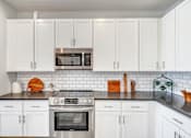 Thumbnail 21 of 30 - Contemporary apartment kitchen with white cabinetry, island and pendant lighting