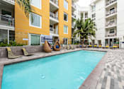 Thumbnail 28 of 34 - A swimming pool in front of a yellow building with a tiled floor.