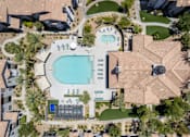 Thumbnail 1 of 63 - A large swimming pool surrounded by a tiled patio and a small building.