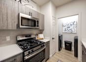 Thumbnail 9 of 63 - A kitchen with a black stove top oven and a microwave above it.