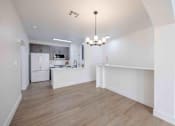 Thumbnail 27 of 63 - A kitchen with a white fridge and a white island with a chandelier hanging from the ceiling.