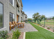 Thumbnail 9 of 58 - A patio with a table and chairs is surrounded by a green fence.