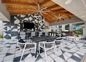 Thumbnail 44 of 58 - A patio with a table and chairs under a wooden ceiling.