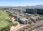 Thumbnail 58 of 58 - an aerial view of apartments and a golf course with mountains in the background
