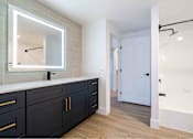 Thumbnail 18 of 58 - a master bathroom with black cabinets and a large mirror