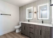 Thumbnail 5 of 58 - A bathroom with a toilet, sink, and mirrors.