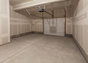 Thumbnail 11 of 23 - A spacious garage with a closed white door and a ceiling light at Bloom Rental Living apartments in Fort Collins, CO.