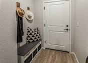 Thumbnail 12 of 23 - A white door is in a hallway with a bench and a hat hanging on the wall at Bloom Rental Living apartments in Fort Collins, CO.