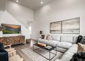 Thumbnail 7 of 12 - A living room with a grey sofa, a black chair, and a coffee table.