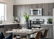Thumbnail 4 of 12 - A modern kitchen with a dining table set for two.