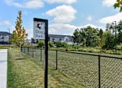 Thumbnail 21 of 79 - A sign for a dog park stands in front of a fence.