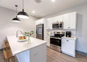 Thumbnail 40 of 79 - A kitchen with white cabinets and a white island with a sink.