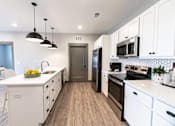 Thumbnail 62 of 79 - A modern kitchen with white cabinets and a wooden floor.