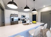 Thumbnail 75 of 79 - A modern kitchen with a large island and white chairs.