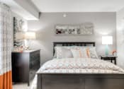Thumbnail 8 of 24 - Large bed with a dresser and artwork on the walls at The Villas at Main Street apartment for rent in Ann Arbor.