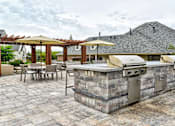 Thumbnail 17 of 24 - Outdoor grilling station with a seating area by the clubhouse at The Villas at Mainstreet apartments in Ann Arbor, MI for rent.