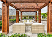 Thumbnail 19 of 24 - A patio with a wooden pergola and wicker furniture.
