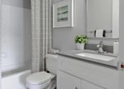 Thumbnail 7 of 30 - A white bathroom with a toilet, sink, and a framed picture on the wall.