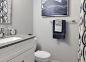 Thumbnail 10 of 30 - A bathroom with a toilet, sink, and a picture on the wall.
