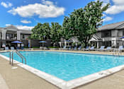 Thumbnail 14 of 30 - A swimming pool surrounded by lounge chairs and umbrellas.