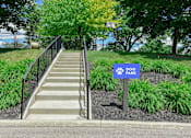 Thumbnail 19 of 30 - A set of stairs leads to a park with a sign on the right.