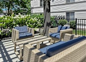 Thumbnail 23 of 30 - A patio with a black railing and a wicker chair with a blue cushion.