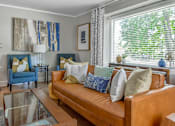 Thumbnail 27 of 30 - A living room with a brown leather couch and blue chairs.