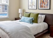 Thumbnail 8 of 22 - A bed with a white comforter and a blue and green pillow.