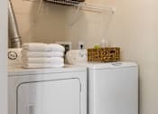 Thumbnail 10 of 22 - A white washing machine and dryer with towels on top of the dryer.