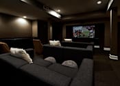 Thumbnail 15 of 22 - A dark room with a large screen and comfortable seating.