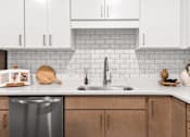 Thumbnail 10 of 61 - A kitchen with a stainless steel dishwasher and wooden cabinets.