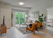 Thumbnail 4 of 61 - A living room with a white couch, a wooden chair, and a television.