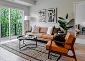 Thumbnail 1 of 61 - A living room with a sofa, a chair, a coffee table, and a potted plant.